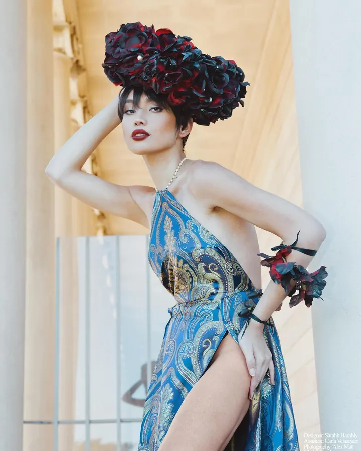 Femme en haut bleu, regardant vers la caméra, cheveux bleus, oreilles percées.