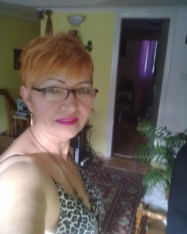 Femme aux cheveux roux en haut blanc, regard intense, photo en gros plan.
