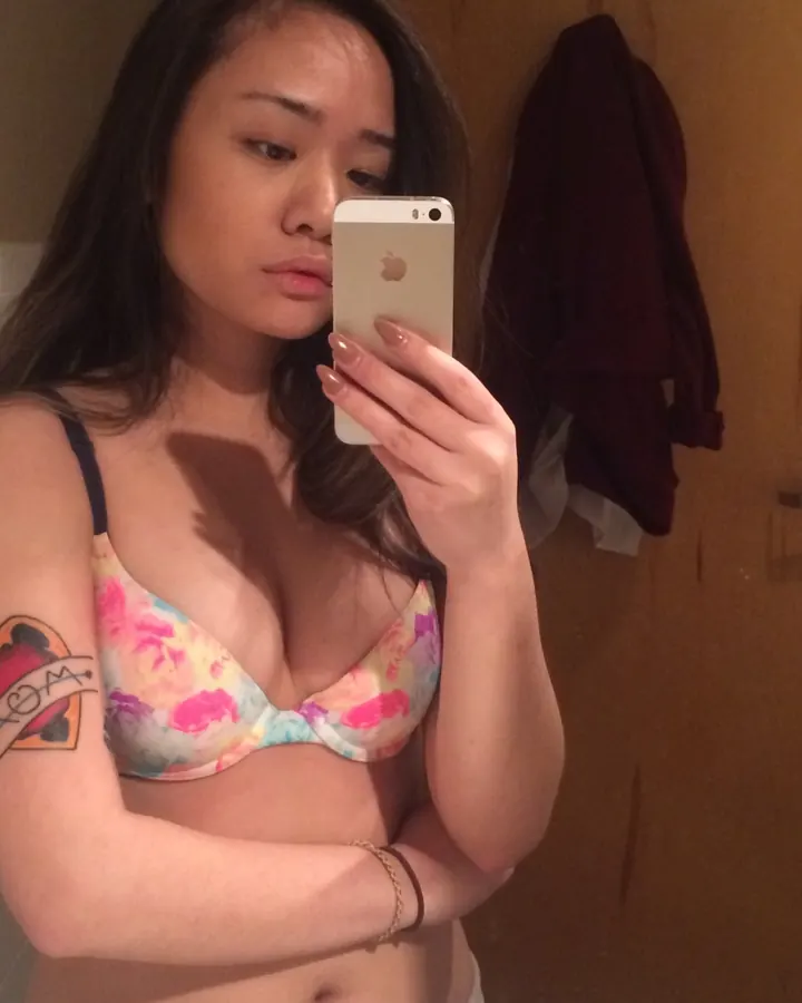 Lola en soutien-gorge fleuri se prenant en photo dans une salle de bain