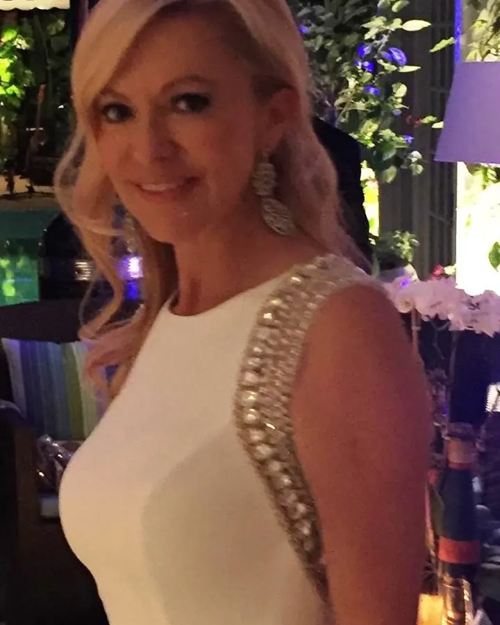 Femme blonde en robe blanche scintillante, souriante, en soirée élégante
