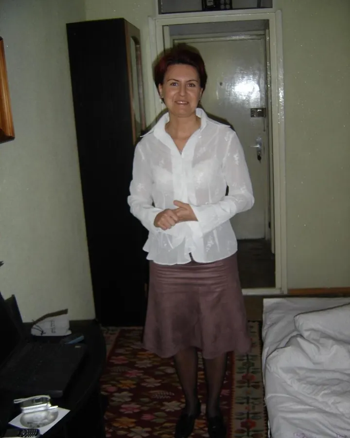 Femme en sous-vêtements noirs, posant sur un lit, vue de dos, dans une chambre aux murs roses