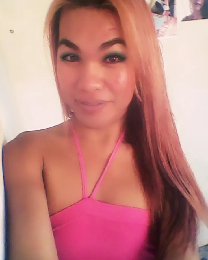 Femme asiatique en haut rose, souriante, regardant l'objectif.